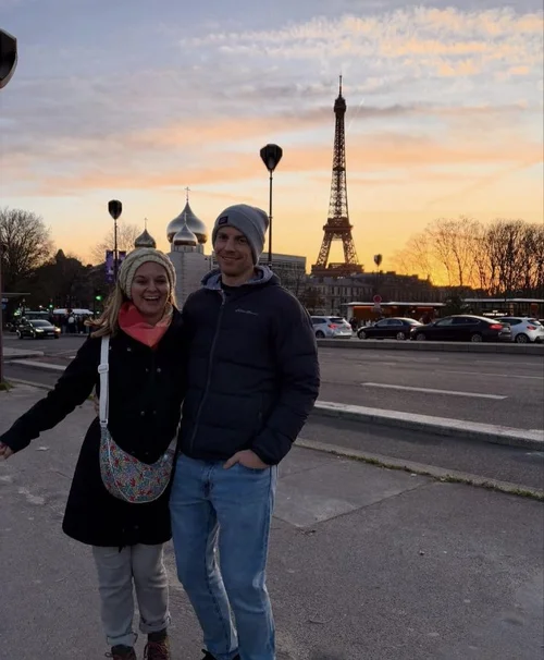 Nick and Caitlin in front of the Eiffel Tower at sunset.
